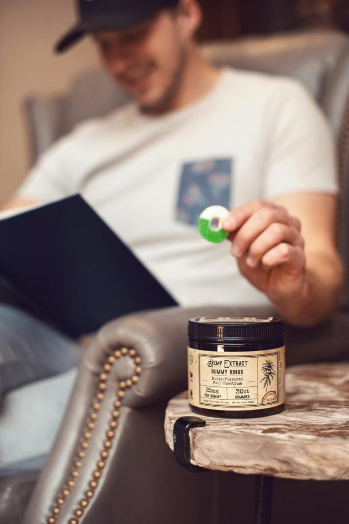 A man relaxes indoors, enjoying a book and holding a CBD gummy in Denver, Colorado.